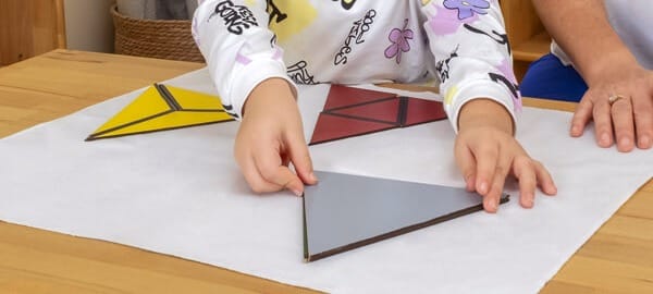 Montessori sınıfında bir çocuğun elleri geometrik şekil materyaliyle çalışıyor