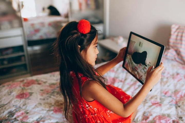 Tabletle ekran kullanan küçük bir çocuk ve yanında ebeveyni