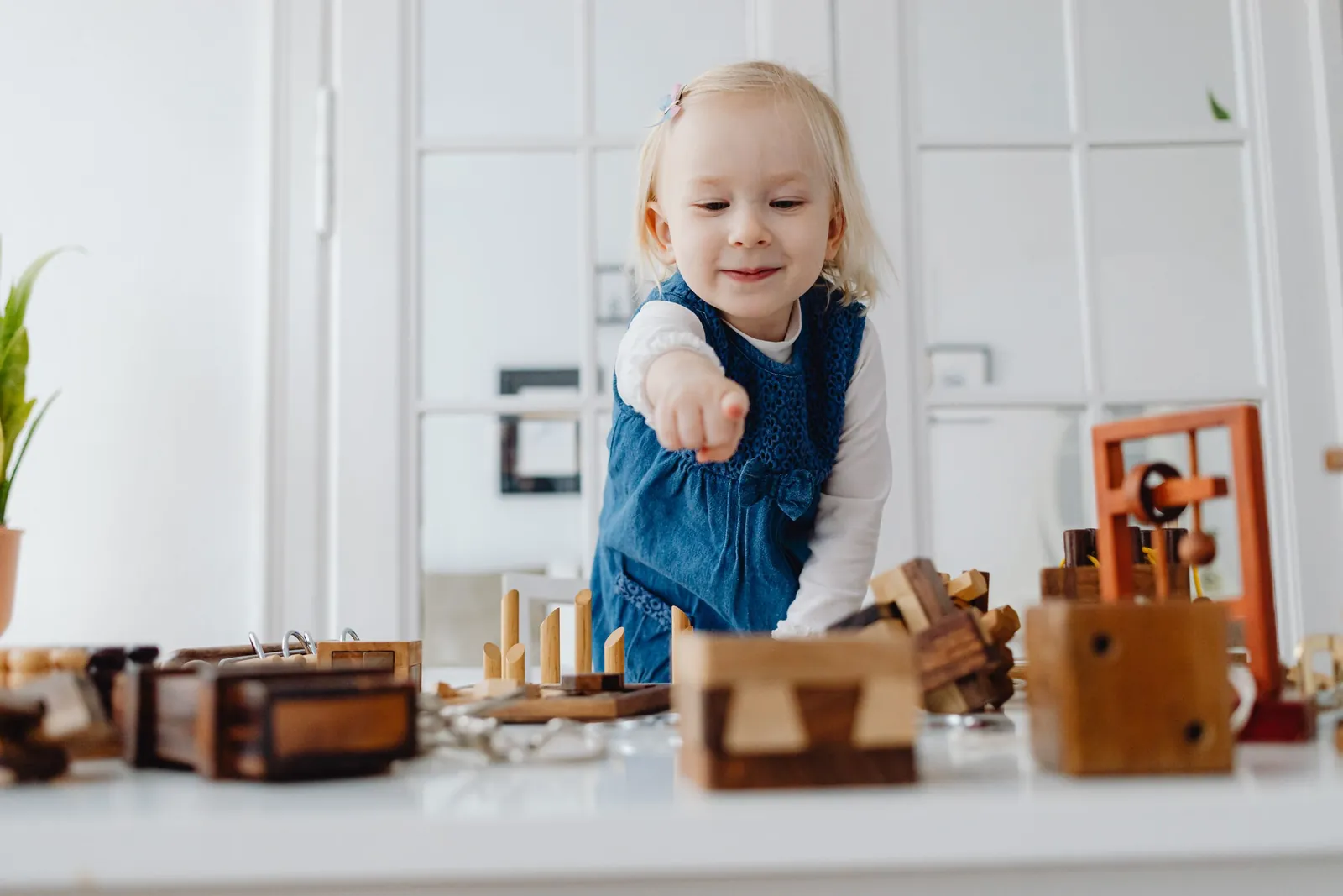 3-5 yaş kız çocuk ahşap oyuncaklarla oynuyor ve parmağıyla gösteriyor