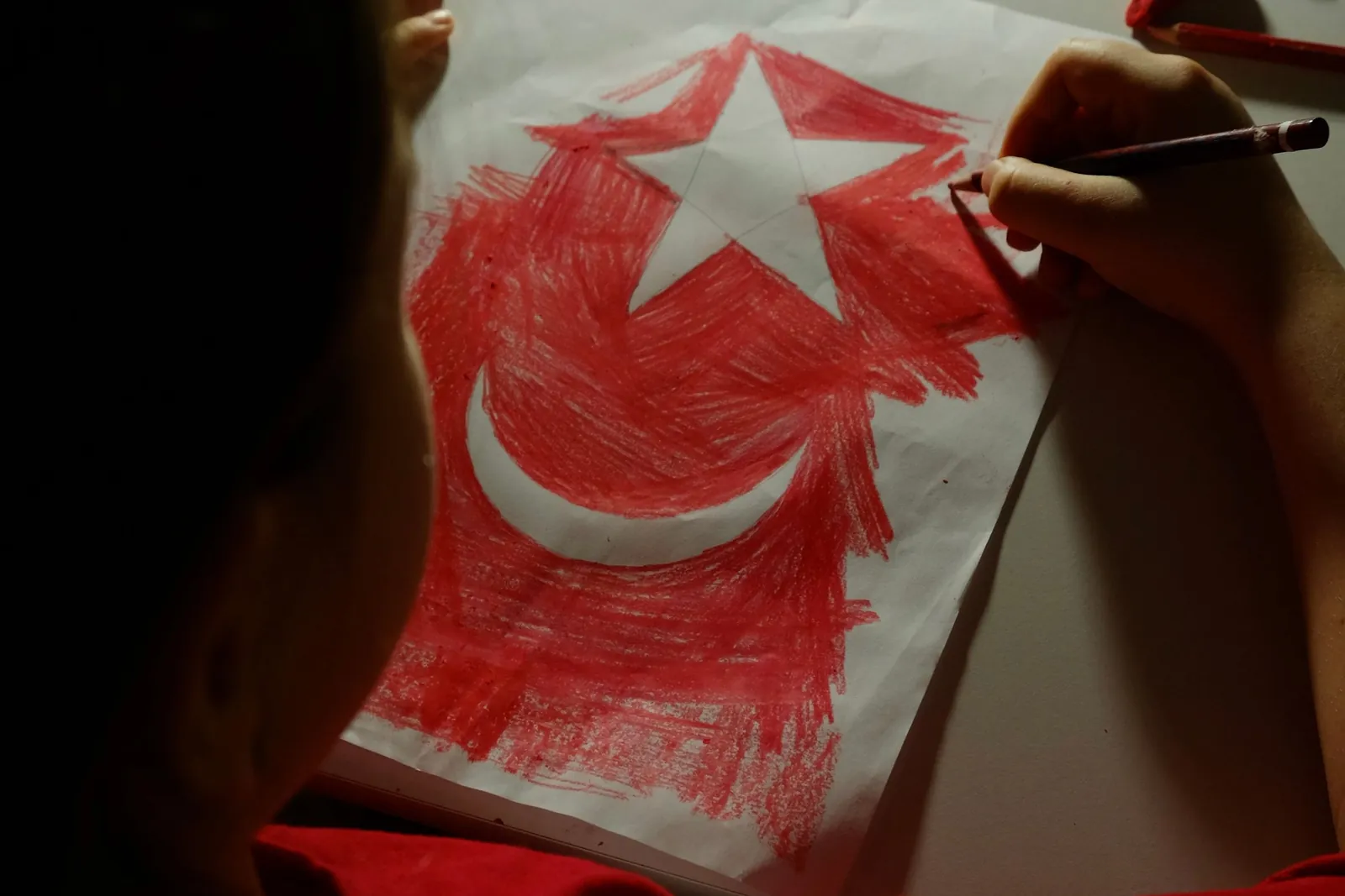 3-5 yaş çocuk kırmızı boya kalemiyle Türk bayrağı çiziyor